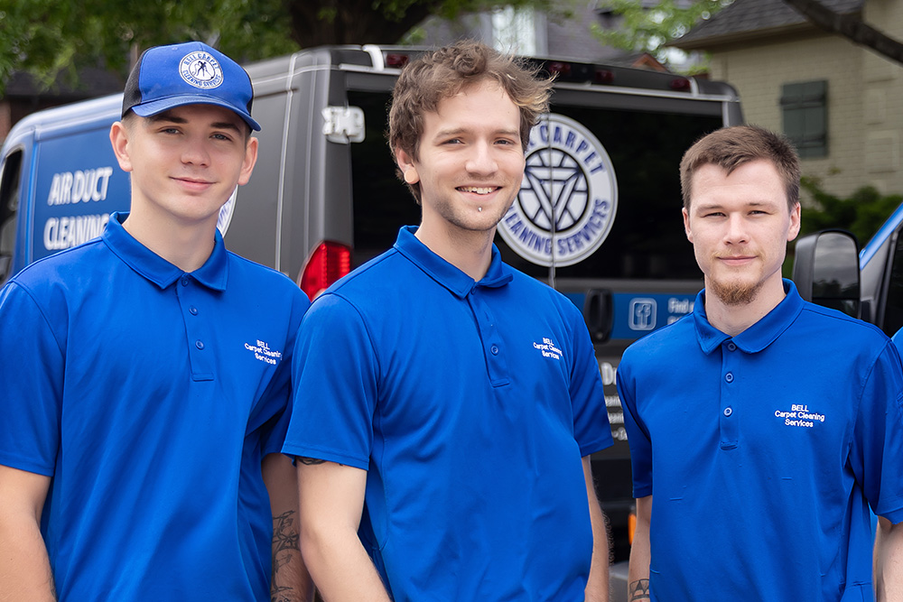 Three Bell Carpet Cleaning Services employees, standing together and smiling.