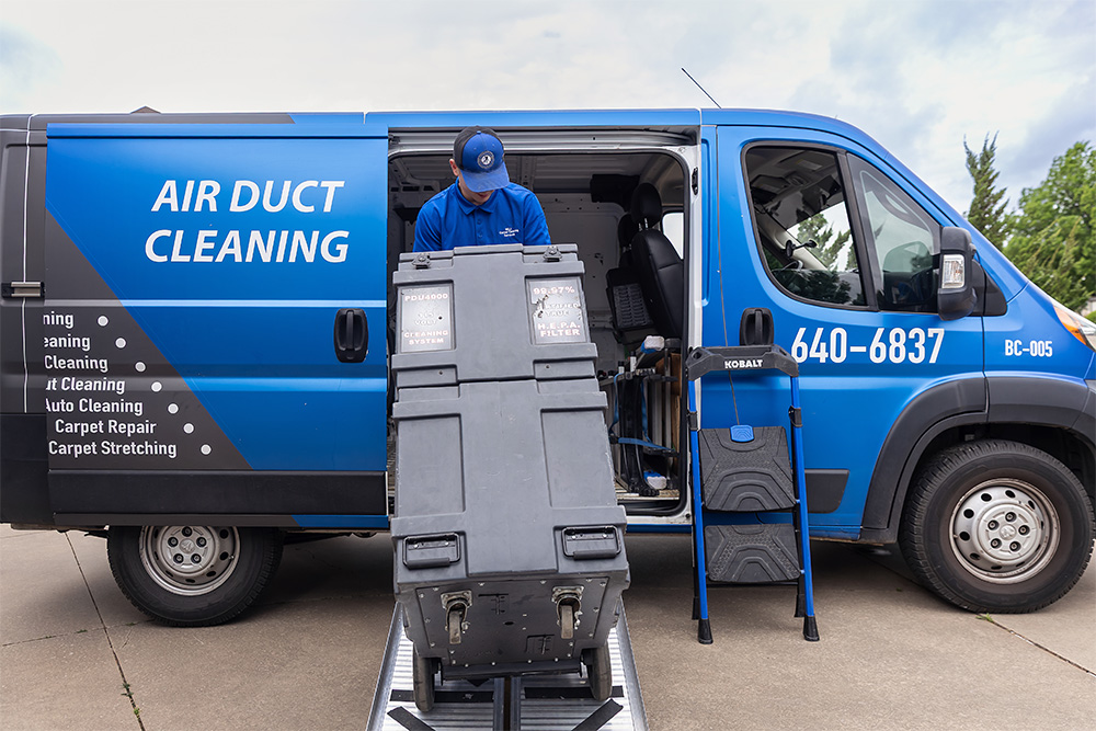 Bell Carpet Cleaning employee emptying equipment for a job from the van on a dolly.