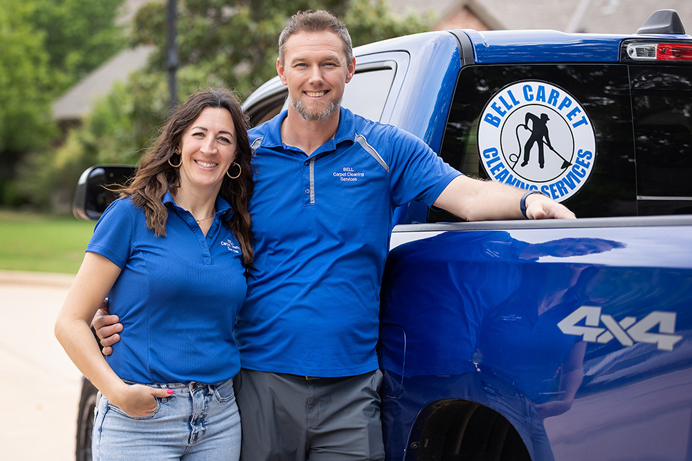 Chris and Sarah Bell posing and smiling beside a Bell Carpet Cleaning truck